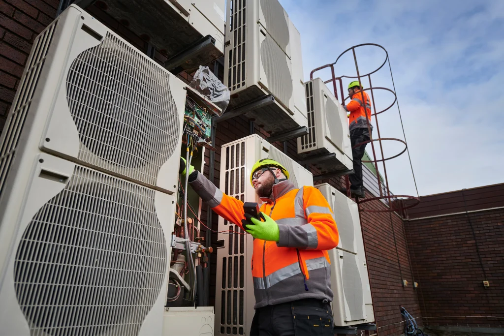 A picture of two men inspecting outdoor air con units
