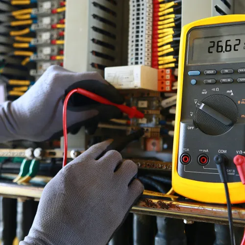 A picture of gloved hands testing an electrical panel with an electrical tester