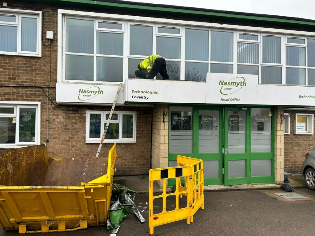 Picture of a man removing former signage on a former commercial entrance