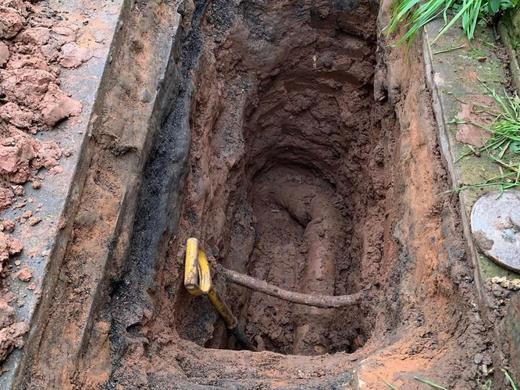 A picture of a spade in a hole following digging down to a pipe
