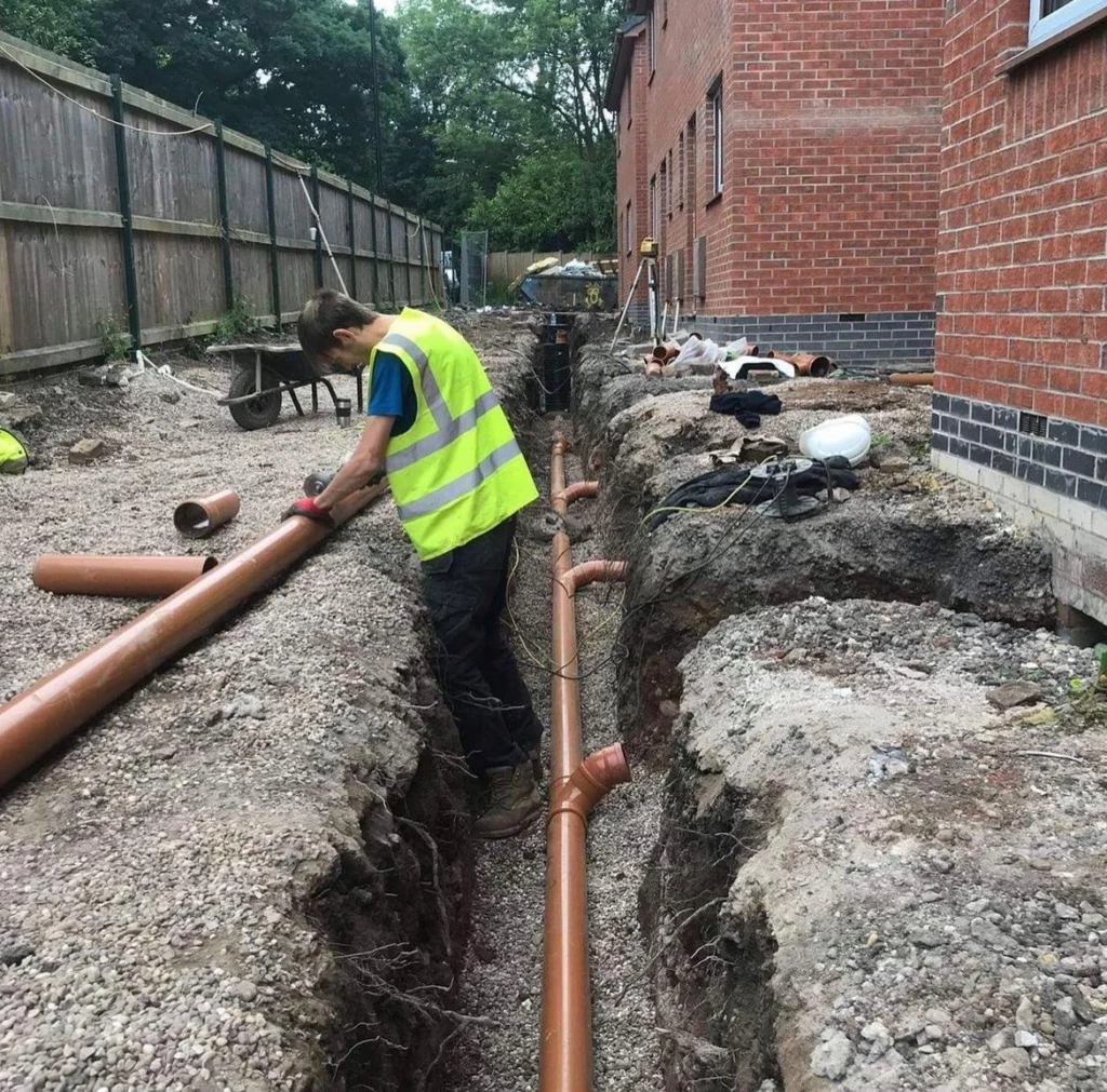 A man fitting pipe work on a housing development