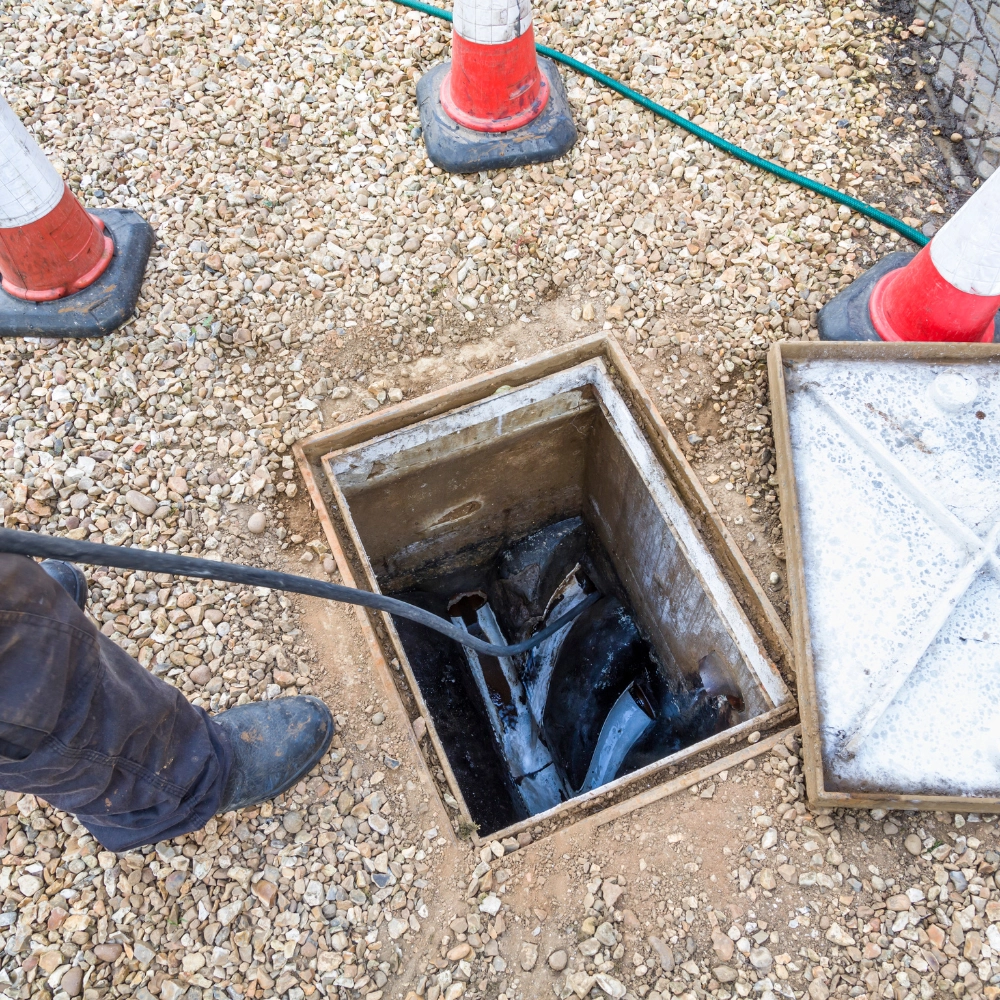 A picture of someone jetting a drain with a drain cover removed