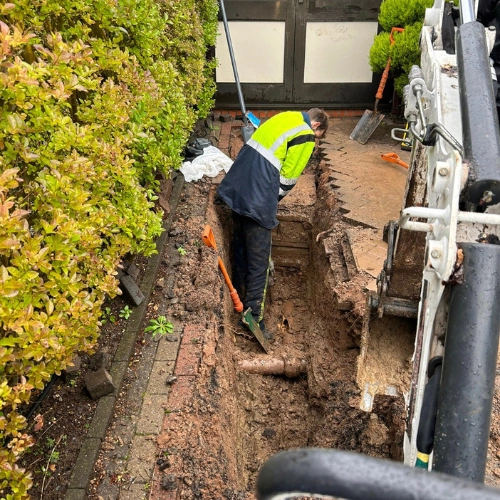 A picture of a drainage engineer for Vikings Building Solutions excavating a damaged drain ahead of a repair