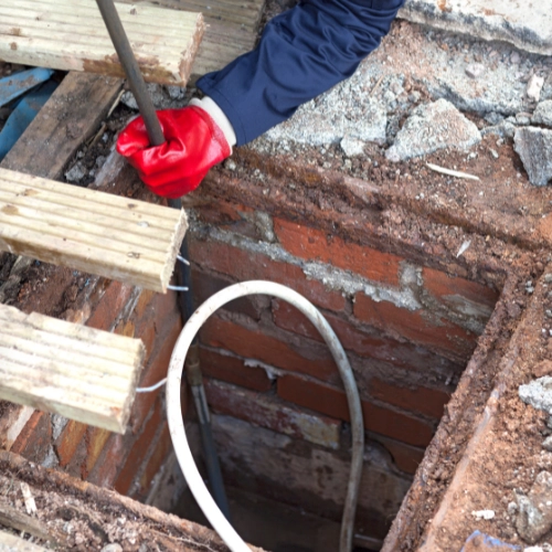 A image of a drainage engineer rodding a drain to clear a drain following an emergency call out